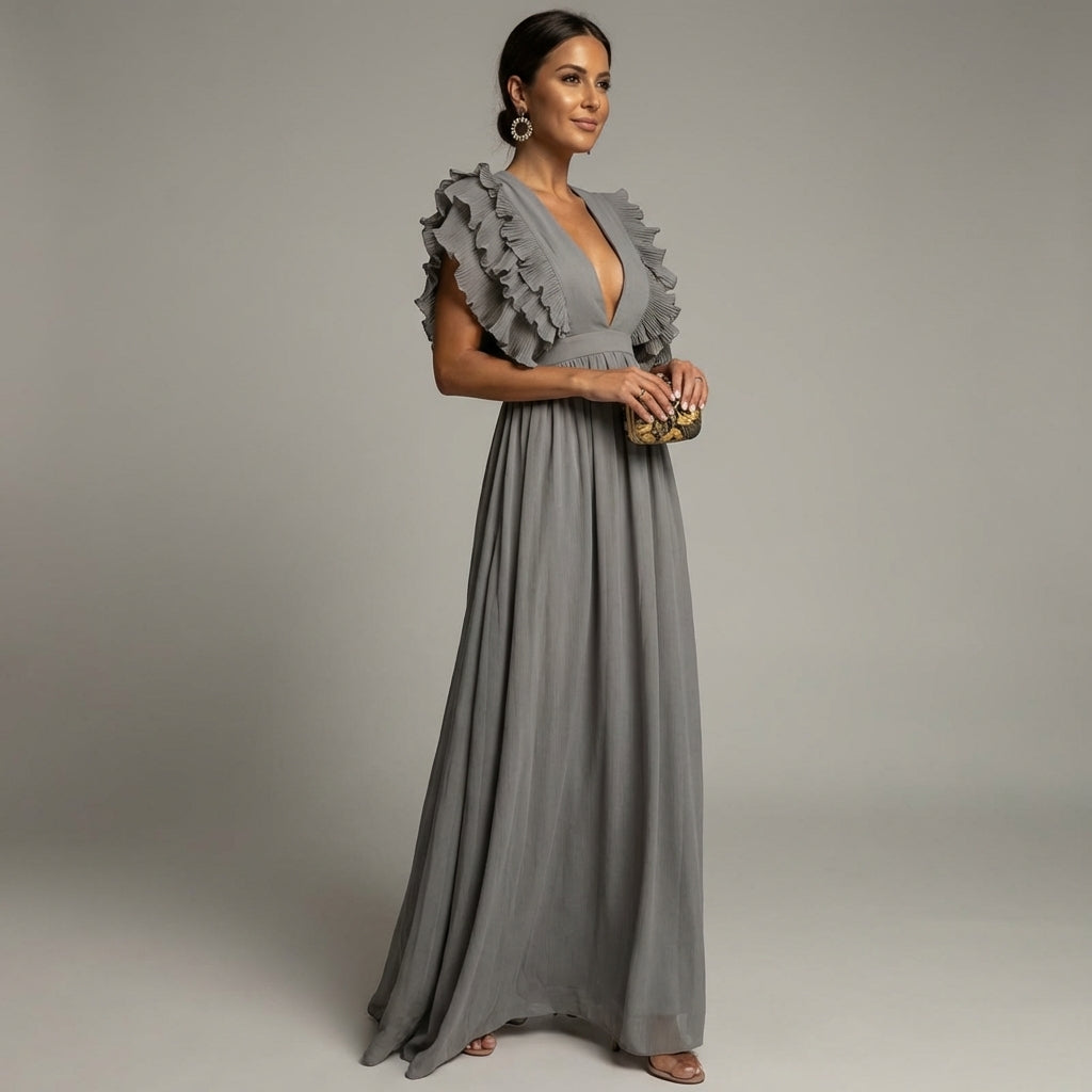 Gray - A woman wearing a floor-length cornflower blue maxi dress with a plunging V-neckline and voluminous, finely pleated ruffle sleeves, holding a gold clutch.