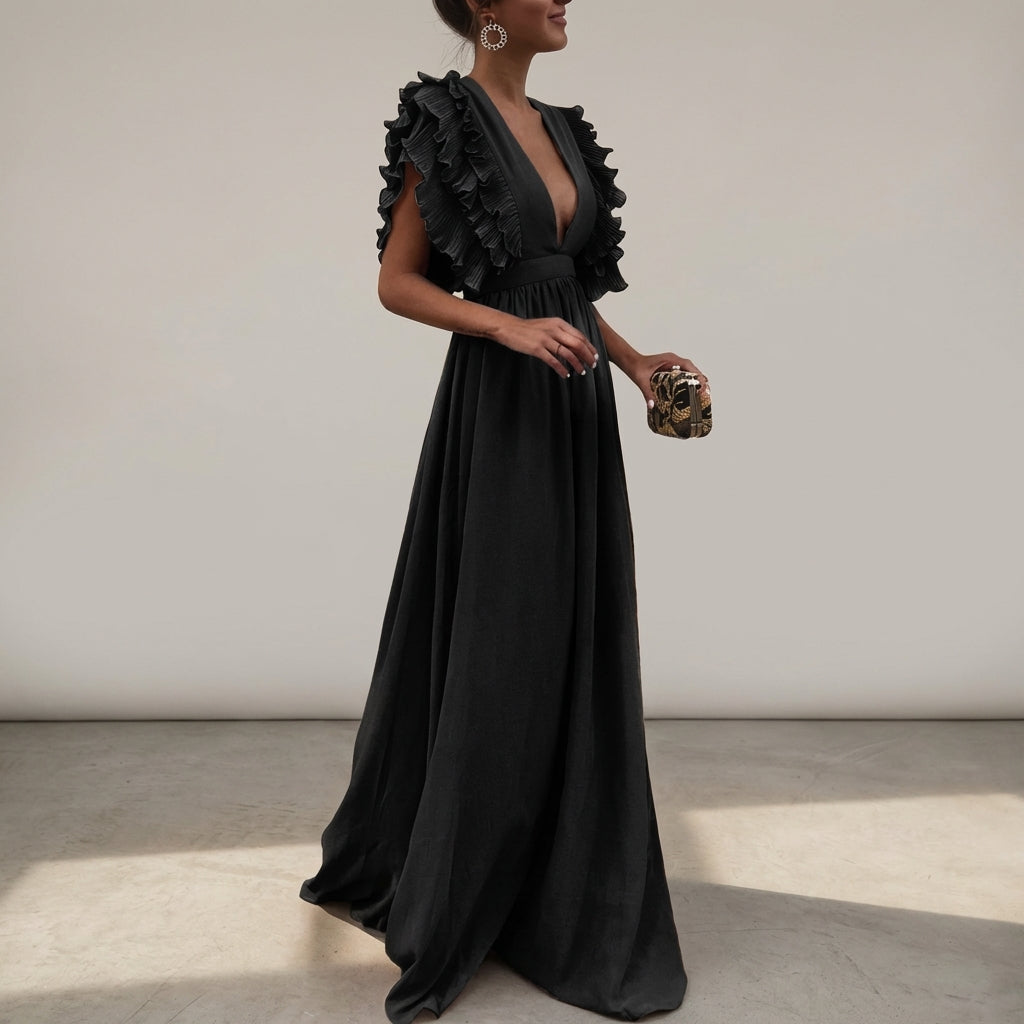 Black - A woman wearing a floor-length cornflower blue maxi dress with a plunging V-neckline and voluminous, finely pleated ruffle sleeves, holding a gold clutch.