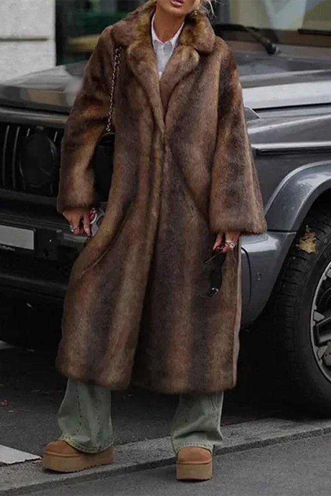Brown - A woman wearing a luxurious, longline brown faux fur coat with oversized lapels, styled over a white collared shirt.