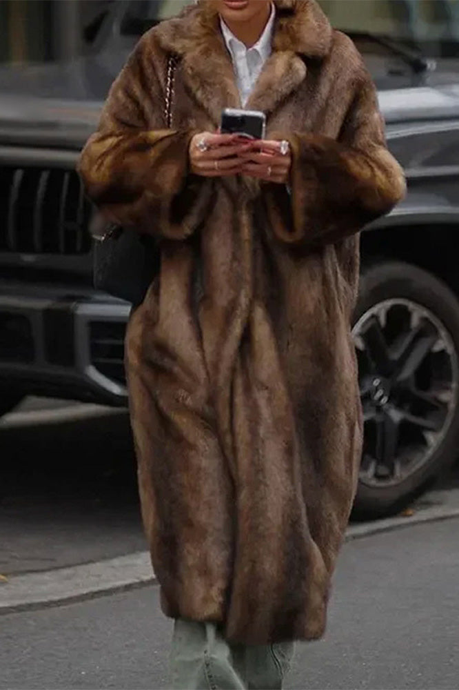 Brown - A woman wearing a luxurious, longline brown faux fur coat with oversized lapels, styled over a white collared shirt.