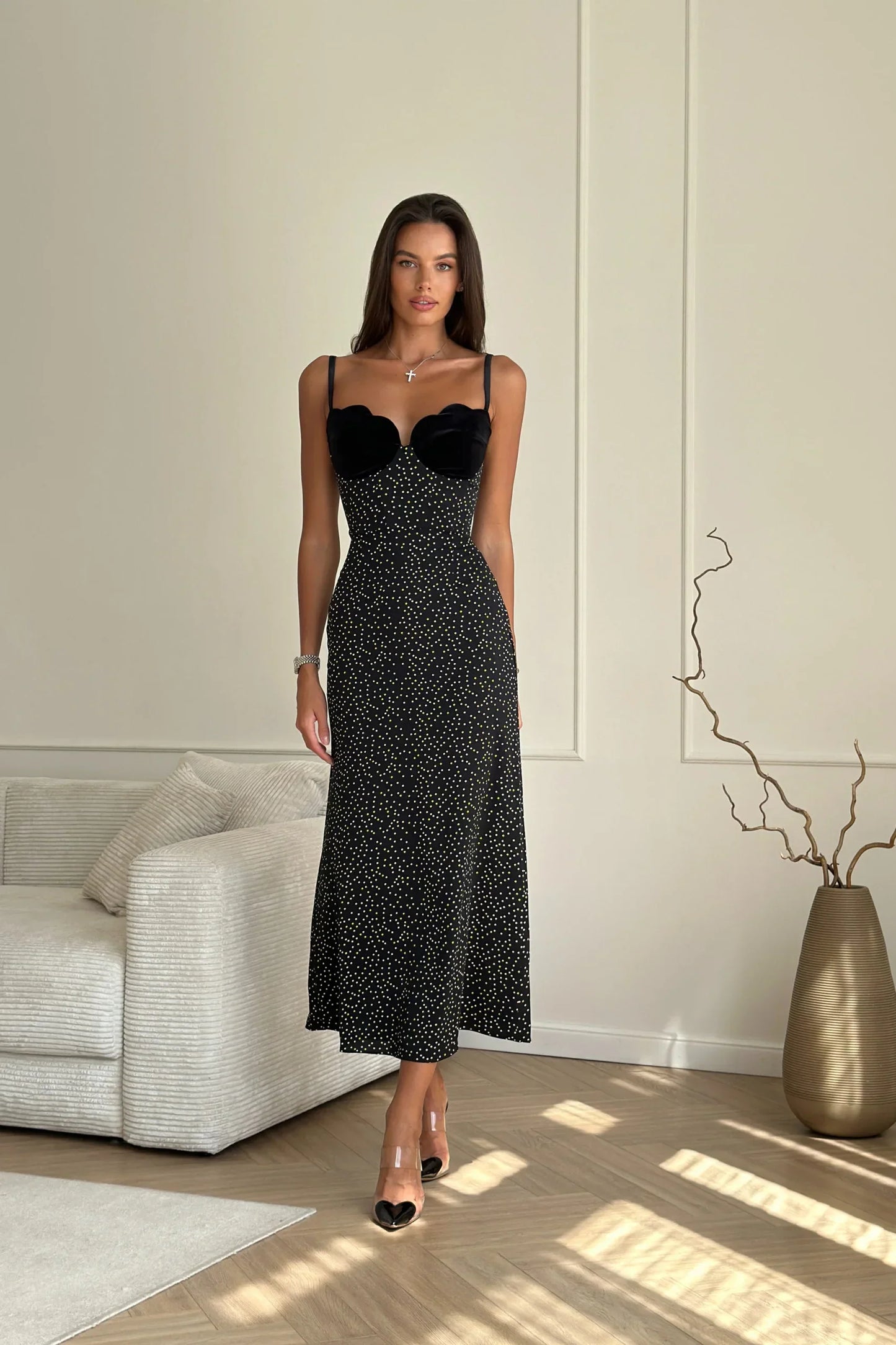 Black - A woman models a black formal maxi dress featuring a velvet sweetheart bustier, spaghetti straps, and an all-over white polka dot pattern.