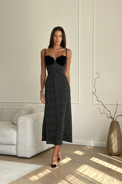 Black - A woman models a black formal maxi dress featuring a velvet sweetheart bustier, spaghetti straps, and an all-over white polka dot pattern.