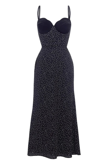 Black - A woman models a black formal maxi dress featuring a velvet sweetheart bustier, spaghetti straps, and an all-over white polka dot pattern.