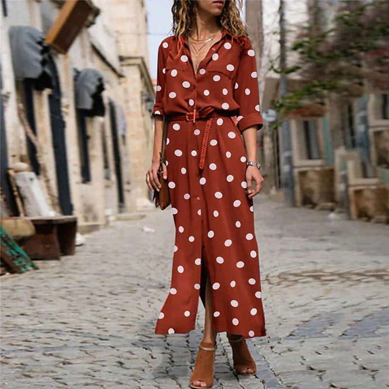 Red - Woman walking outdoors wearing a long polka dot button-front shirt dress with long sleeves and chest pockets