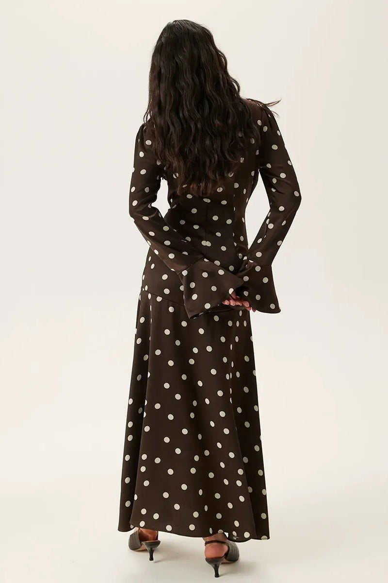 Brown - A woman wearing a brown and white polka dot satin midi dress featuring a V-neckline, ruched front detailing, and flared long sleeves.