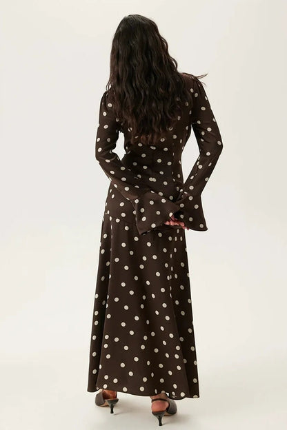 Brown - A woman wearing a brown and white polka dot satin midi dress featuring a V-neckline, ruched front detailing, and flared long sleeves.