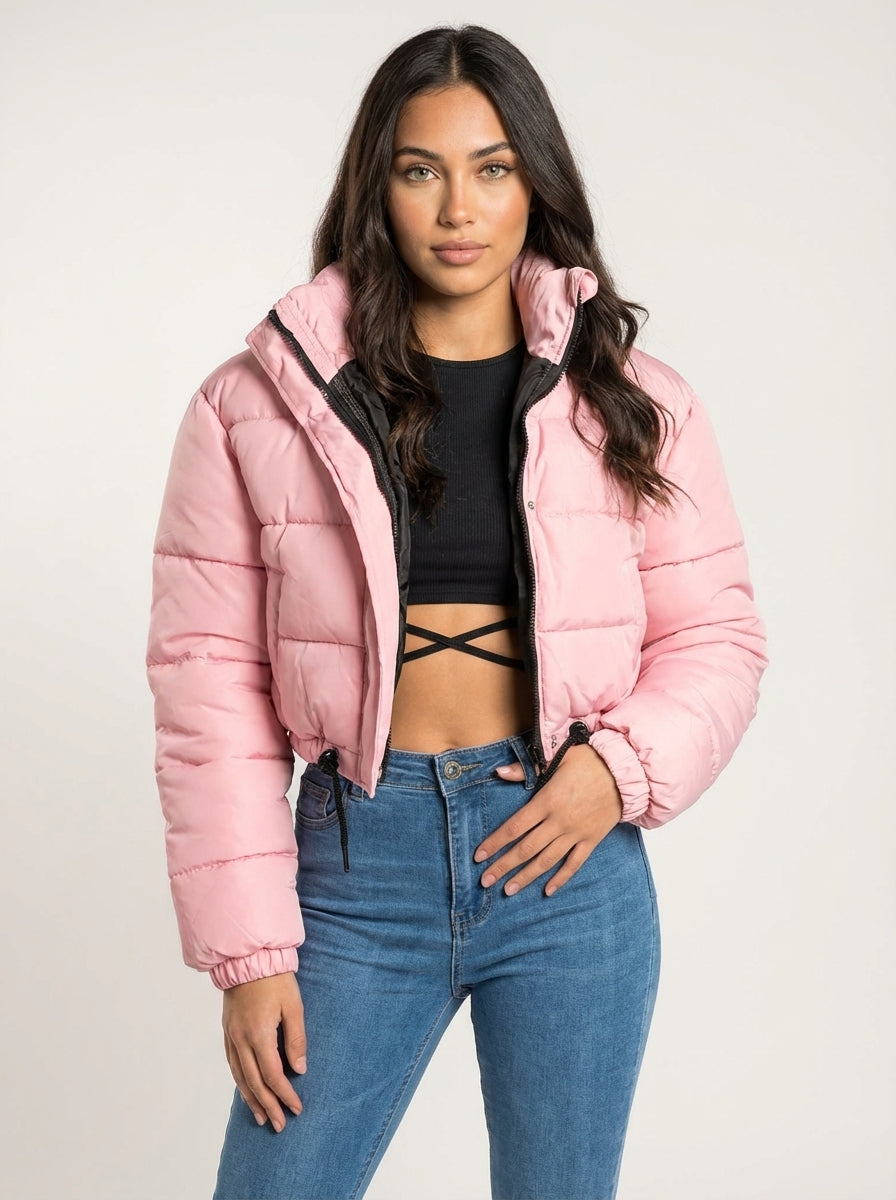 Pink - A woman wearing a dark brown cropped puffer jacket with an integrated hood, featuring horizontal quilting, a front zip closure, and adjustable drawstring toggles at the hem, paired with black high-waisted jeans.