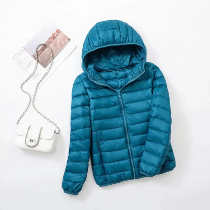 Pink - A woman wearing an off-white hooded puffer jacket with horizontal quilting, zipped up, paired with blue jeans against a plain white background.