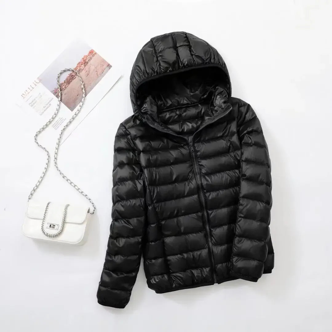 Pink - A woman wearing an off-white hooded puffer jacket with horizontal quilting, zipped up, paired with blue jeans against a plain white background.