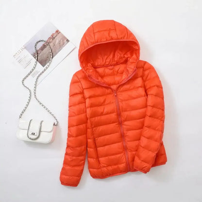 Pink - A woman wearing an off-white hooded puffer jacket with horizontal quilting, zipped up, paired with blue jeans against a plain white background.
