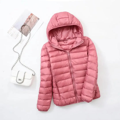 Pink - A woman wearing an off-white hooded puffer jacket with horizontal quilting, zipped up, paired with blue jeans against a plain white background.