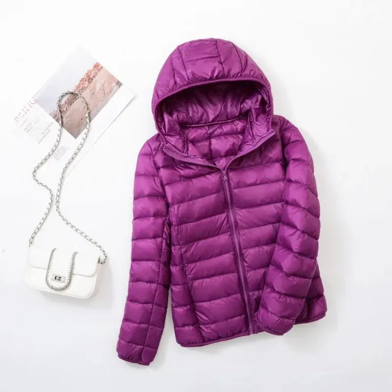 Pink - A woman wearing an off-white hooded puffer jacket with horizontal quilting, zipped up, paired with blue jeans against a plain white background.