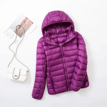 Pink - A woman wearing an off-white hooded puffer jacket with horizontal quilting, zipped up, paired with blue jeans against a plain white background.