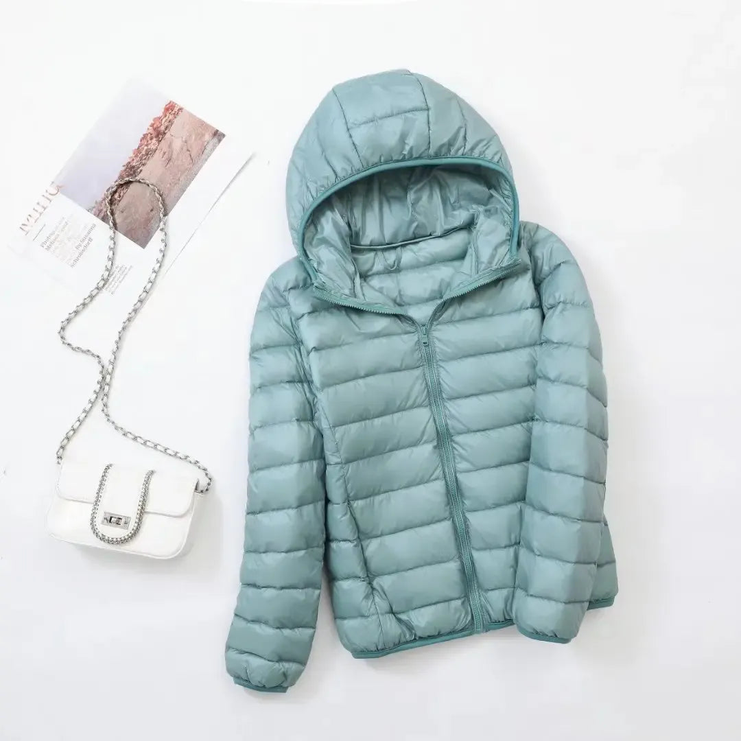 Pink - A woman wearing an off-white hooded puffer jacket with horizontal quilting, zipped up, paired with blue jeans against a plain white background.