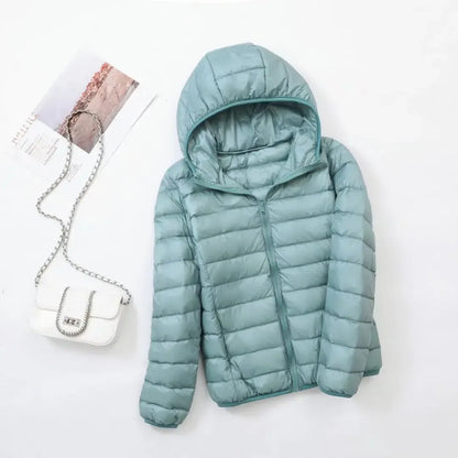 Pink - A woman wearing an off-white hooded puffer jacket with horizontal quilting, zipped up, paired with blue jeans against a plain white background.