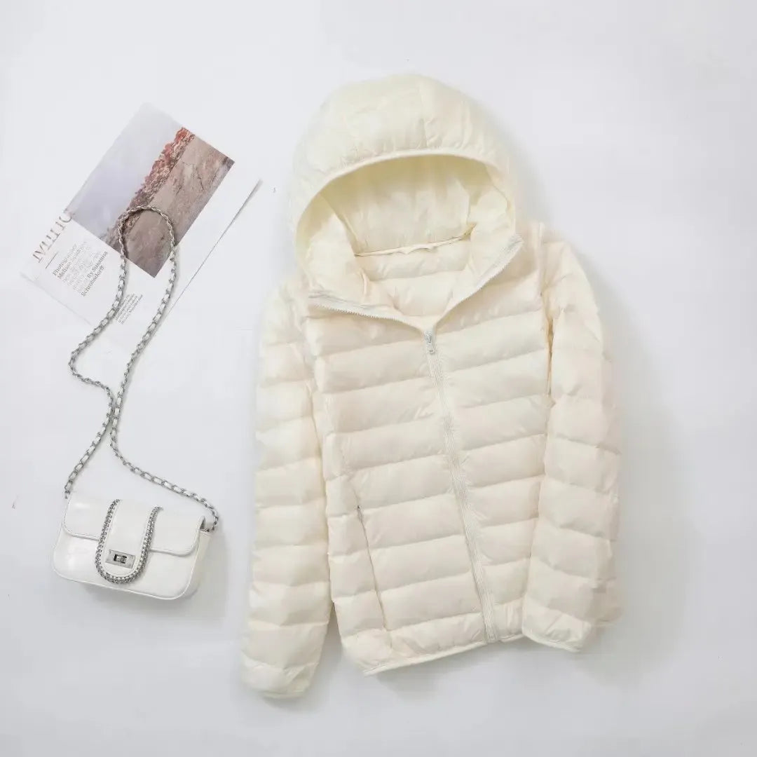 Pink - A woman wearing an off-white hooded puffer jacket with horizontal quilting, zipped up, paired with blue jeans against a plain white background.
