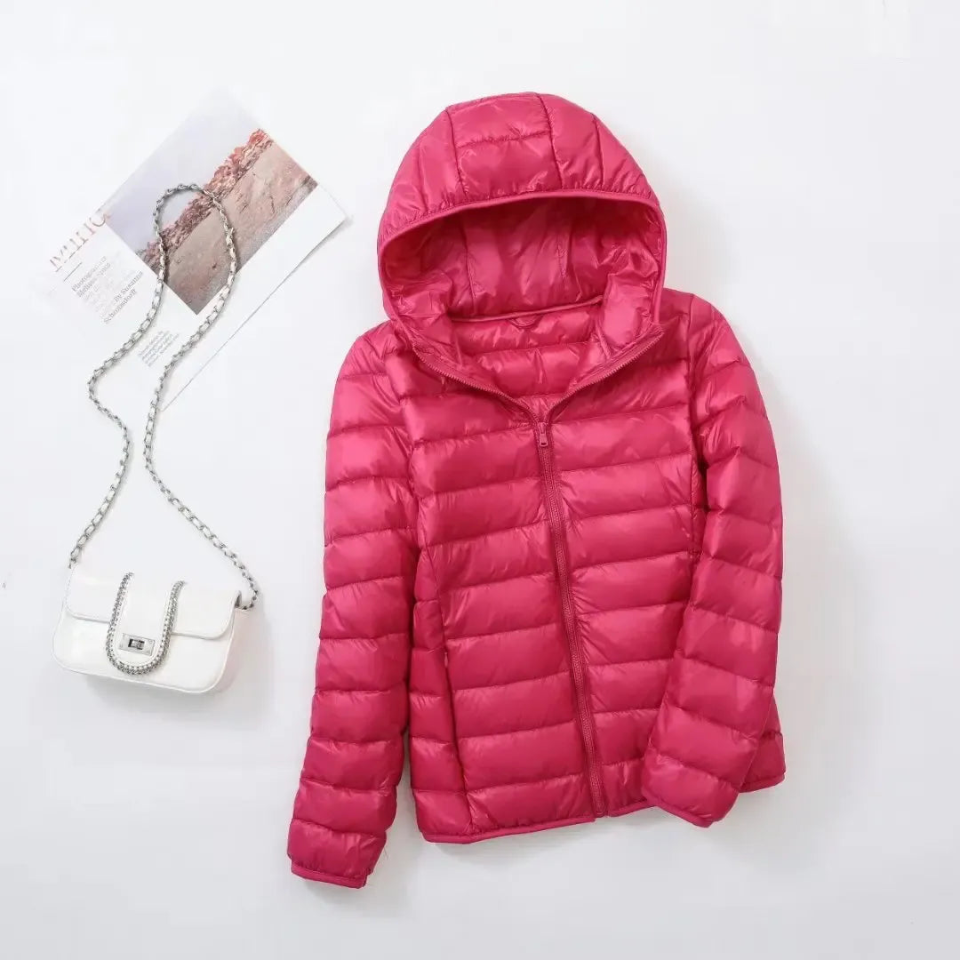 Pink - A woman wearing an off-white hooded puffer jacket with horizontal quilting, zipped up, paired with blue jeans against a plain white background.