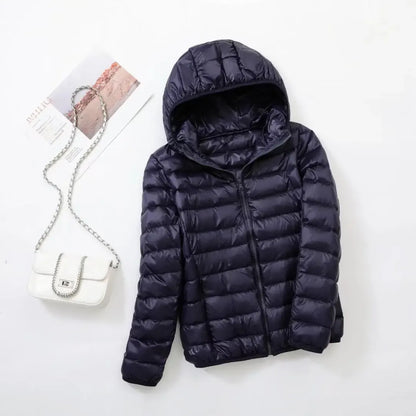 Pink - A woman wearing an off-white hooded puffer jacket with horizontal quilting, zipped up, paired with blue jeans against a plain white background.