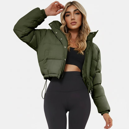 Army Green - A woman wearing a dark brown cropped puffer jacket with an integrated hood, featuring horizontal quilting, a front zip closure, and adjustable drawstring toggles at the hem, paired with black high-waisted jeans.