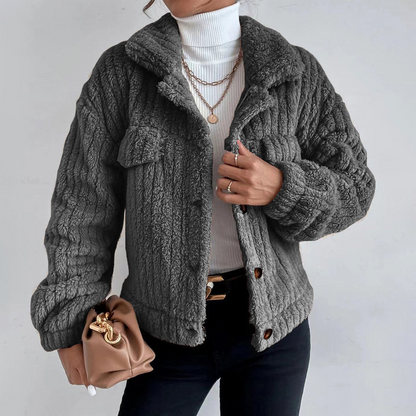 Dark Gray - Women's black heavyweight faux shearling jacket featuring a collared neckline, tortoiseshell buttons, dual chest pockets, and a distinct vertical ribbed texture, styled over a white turtleneck.