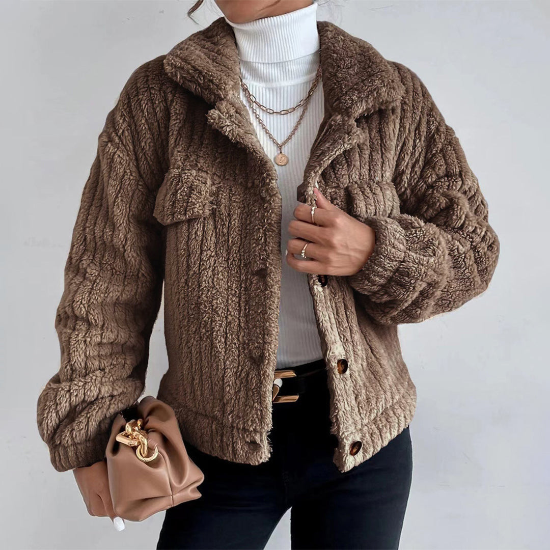 Brown - Women's black heavyweight faux shearling jacket featuring a collared neckline, tortoiseshell buttons, dual chest pockets, and a distinct vertical ribbed texture, styled over a white turtleneck.