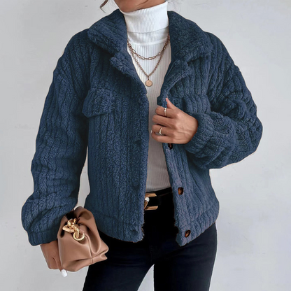 Dark Blue - Women's black heavyweight faux shearling jacket featuring a collared neckline, tortoiseshell buttons, dual chest pockets, and a distinct vertical ribbed texture, styled over a white turtleneck.