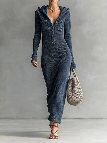 Navy - A woman wearing a long-sleeve, blue-grey ribbed knit maxi dress featuring a hood, a button-down neckline, and chest flap pockets, paired with a woven tote bag.
