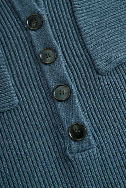 Green - A woman wearing a long-sleeve, blue-grey ribbed knit maxi dress featuring a hood, a button-down neckline, and chest flap pockets, paired with a woven tote bag.