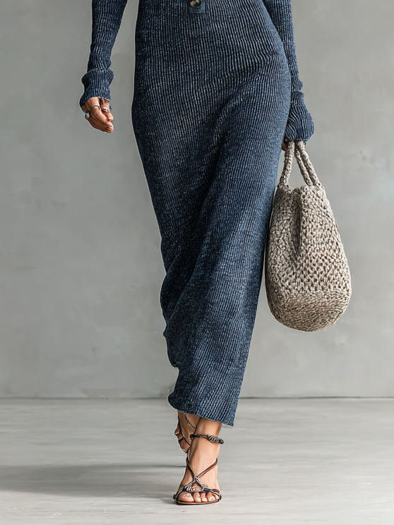 Navy - A woman wearing a long-sleeve, blue-grey ribbed knit maxi dress featuring a hood, a button-down neckline, and chest flap pockets, paired with a woven tote bag.