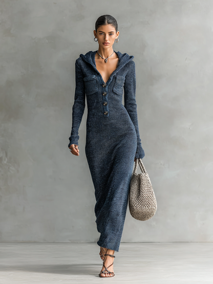 Navy - A woman wearing a long-sleeve, blue-grey ribbed knit maxi dress featuring a hood, a button-down neckline, and chest flap pockets, paired with a woven tote bag.