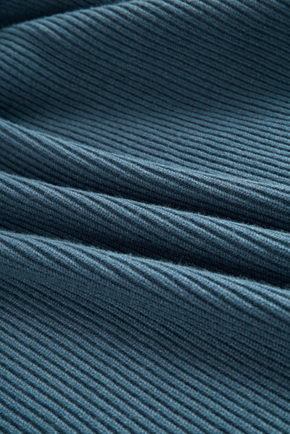 Green - A woman wearing a long-sleeve, blue-grey ribbed knit maxi dress featuring a hood, a button-down neckline, and chest flap pockets, paired with a woven tote bag.