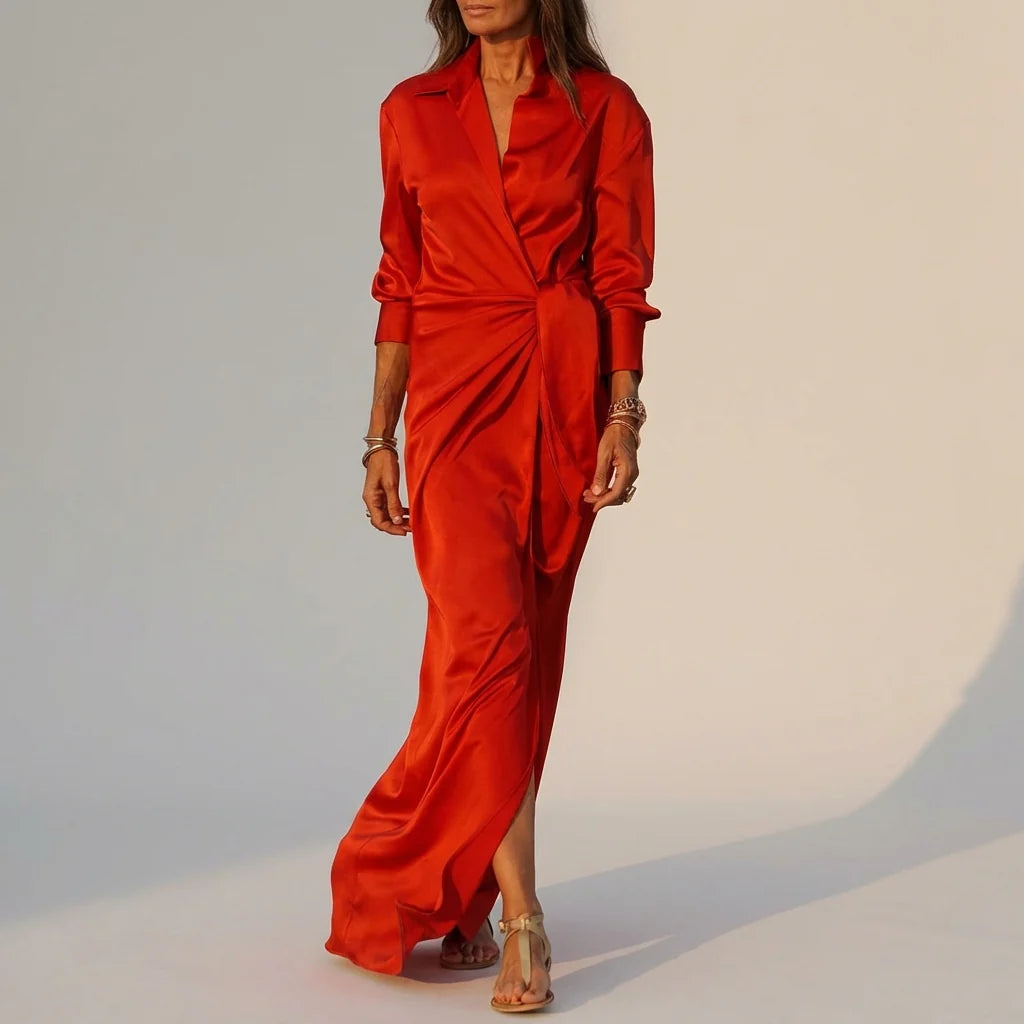 Red - A woman wearing a long-sleeve, mustard-yellow satin wrap maxi dress with a collar, tied waist detail, and front split, posing against a neutral grey background.