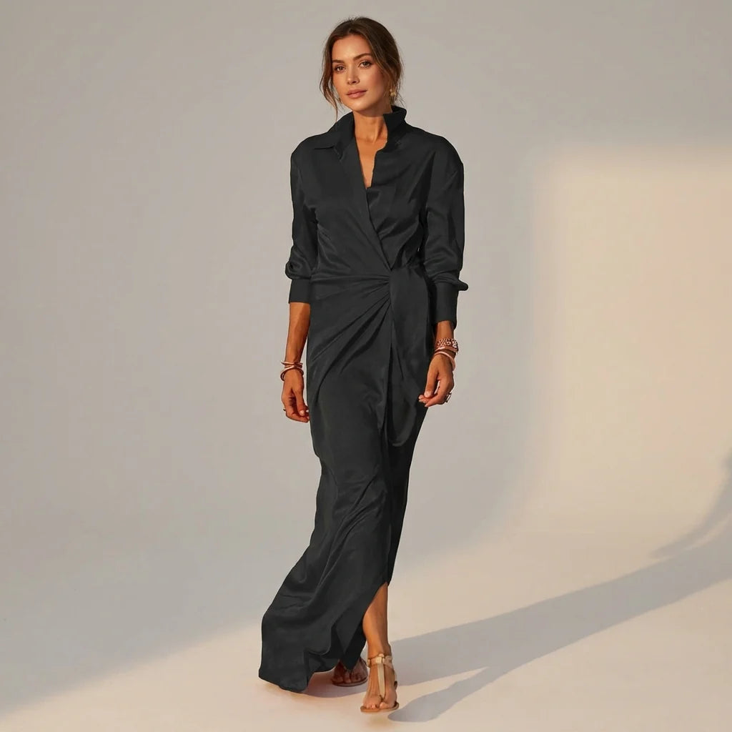 Black - A woman wearing a long-sleeve, mustard-yellow satin wrap maxi dress with a collar, tied waist detail, and front split, posing against a neutral grey background.
