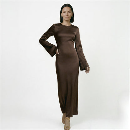 Brown - A woman wearing a long-sleeve chocolate brown satin maxi dress with a round neckline and flared cuffs, standing against a plain white background.
