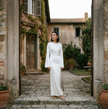 Brown - A woman wearing a long-sleeve chocolate brown satin maxi dress with a round neckline and flared cuffs, standing against a plain white background.