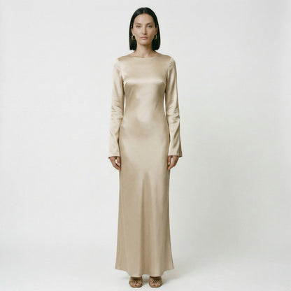 Sand - A woman wearing a long-sleeve chocolate brown satin maxi dress with a round neckline and flared cuffs, standing against a plain white background.