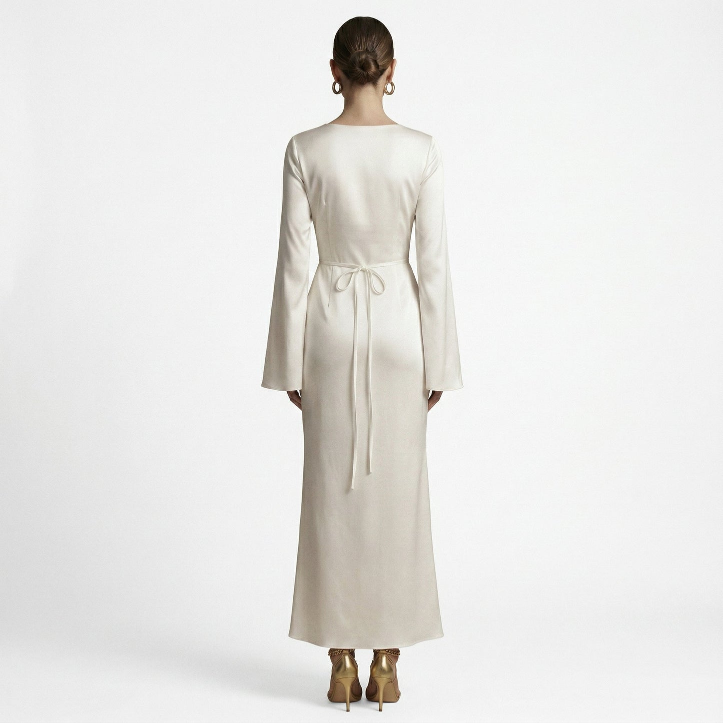 Sand - A woman wearing a long-sleeve chocolate brown satin maxi dress with a round neckline and flared cuffs, standing against a plain white background.