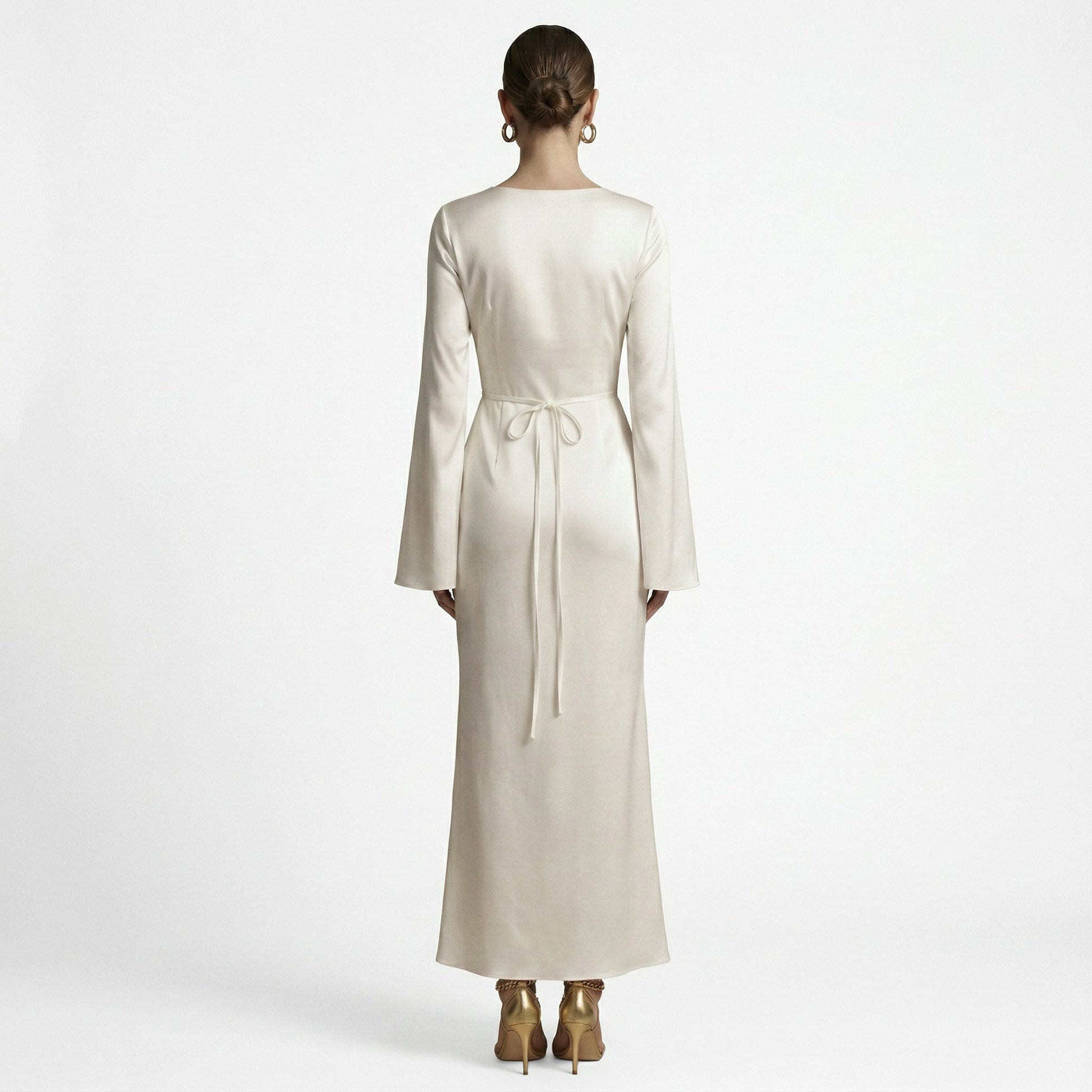 Sand - A woman wearing a long-sleeve chocolate brown satin maxi dress with a round neckline and flared cuffs, standing against a plain white background.