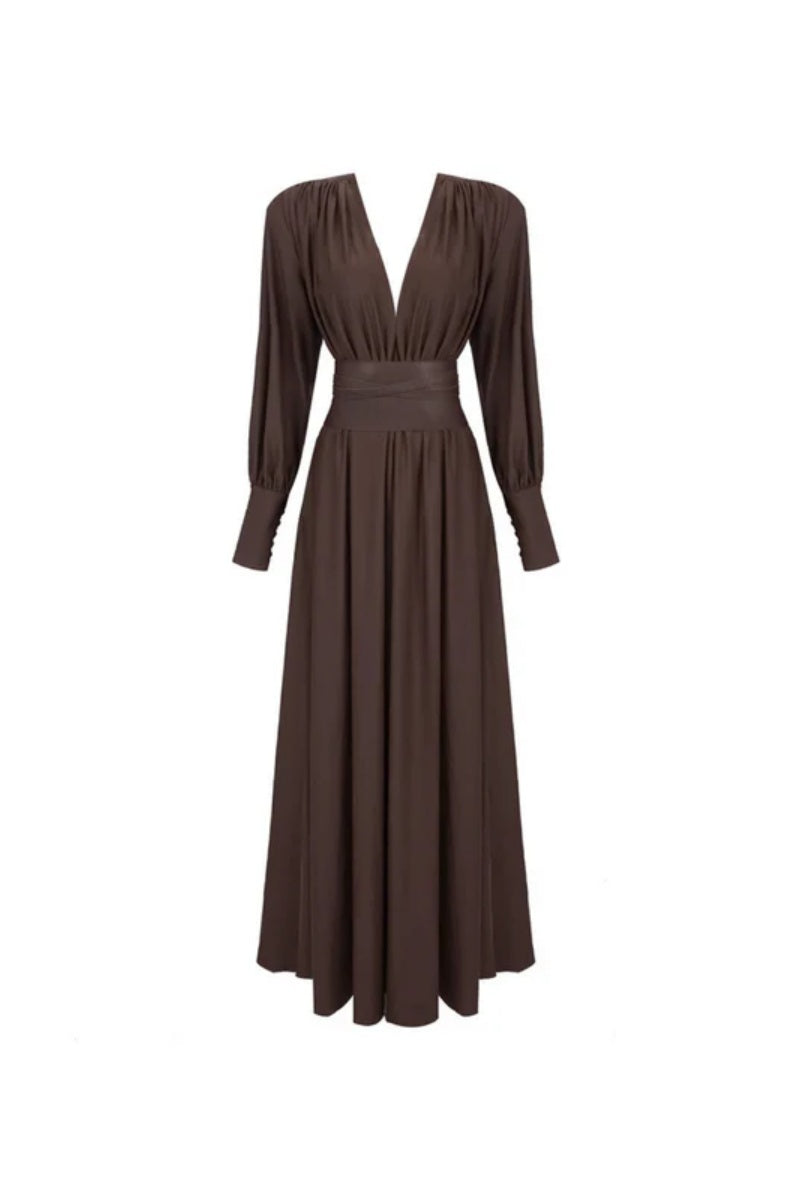 Brown - A woman wearing a chocolate brown satin maxi dress with a plunging V-neckline, ruched bodice, wide structured waist panel, and long bishop sleeves, standing against a city skyline background.