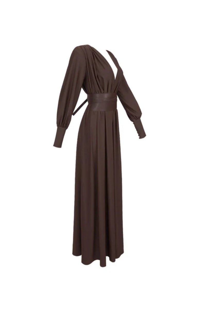 Brown - A woman wearing a chocolate brown satin maxi dress with a plunging V-neckline, ruched bodice, wide structured waist panel, and long bishop sleeves, standing against a city skyline background.