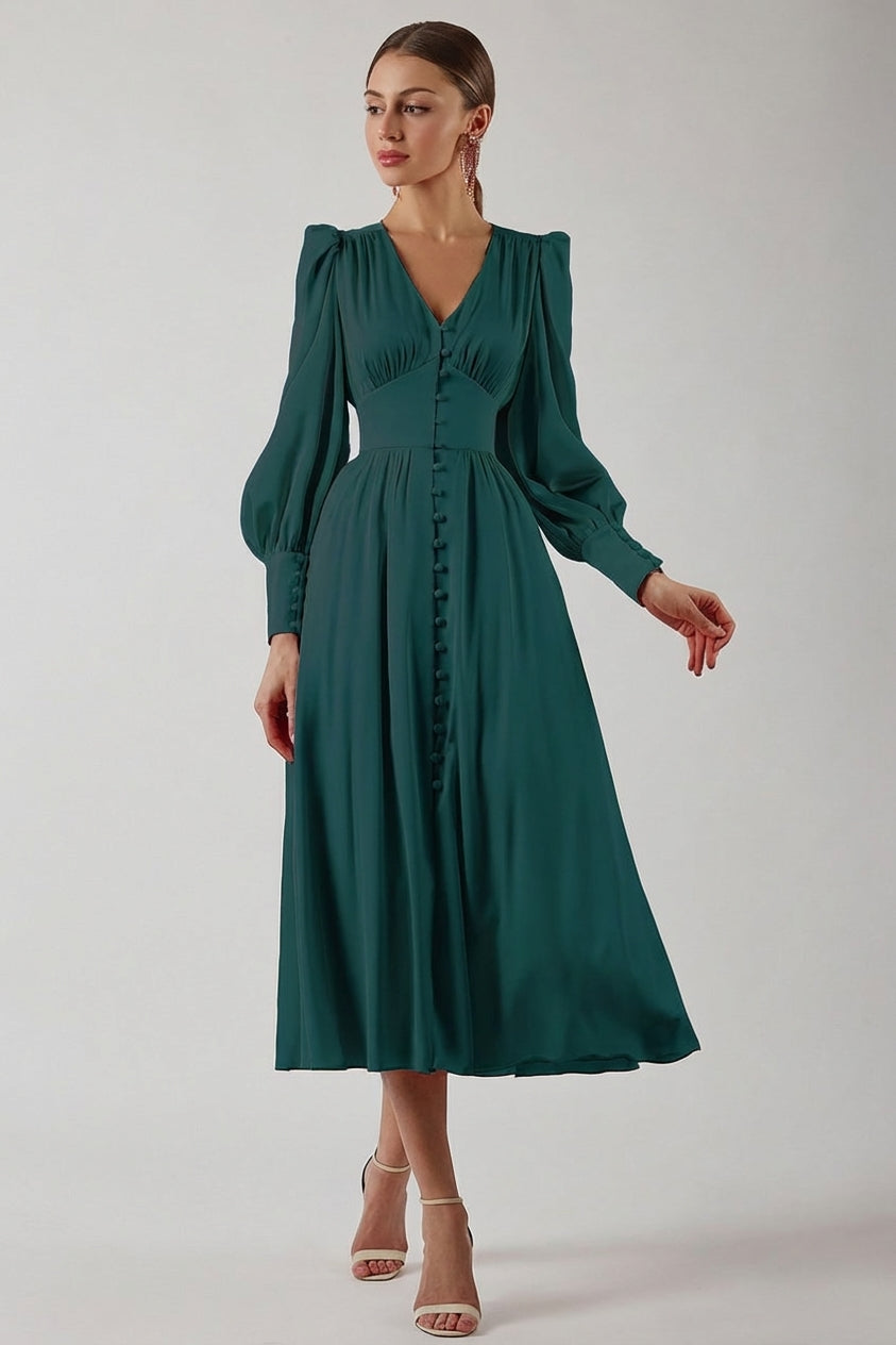 A woman wearing a taupe-coloured satin midi dress featuring a V-neckline, a row of self-covered buttons down the front, a cinched waistband, and long bishop sleeves with extended buttoned cuffs.