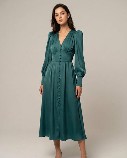 Green - A woman wearing a taupe-coloured satin midi dress featuring a V-neckline, a row of self-covered buttons down the front, a cinched waistband, and long bishop sleeves with extended buttoned cuffs.