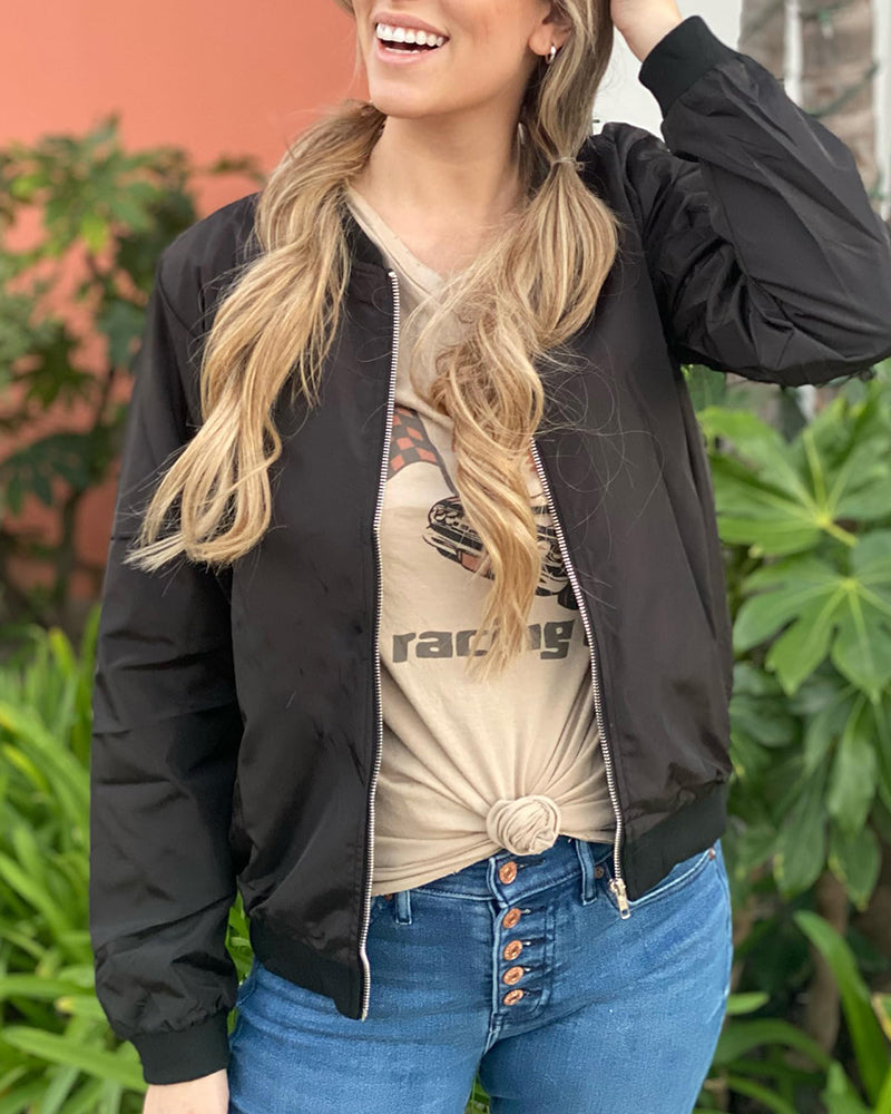 Black - A woman wearing a black, lightweight zip-front bomber jacket with ribbed trims, styled casually open over a t-shirt and denim jeans.