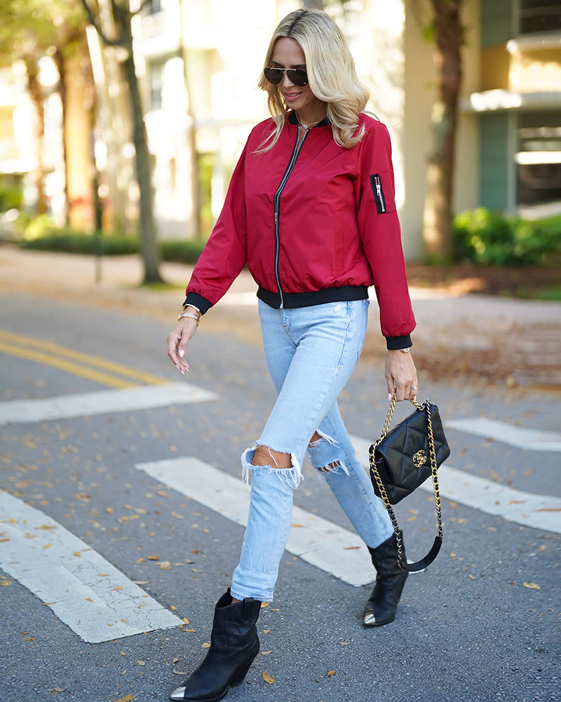 Wine Red - A woman wearing a black, lightweight zip-front bomber jacket with ribbed trims, styled casually open over a t-shirt and denim jeans.