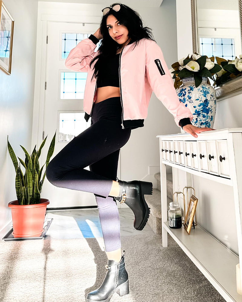 Pink - A woman wearing a black, lightweight zip-front bomber jacket with ribbed trims, styled casually open over a t-shirt and denim jeans.