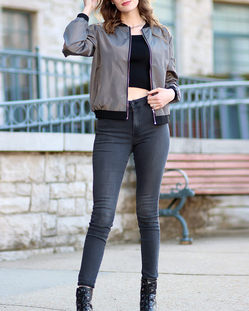 Gray - A woman wearing a black, lightweight zip-front bomber jacket with ribbed trims, styled casually open over a t-shirt and denim jeans.