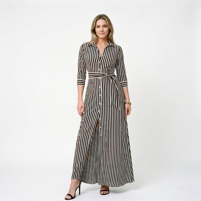 Black - A woman wearing a black and white vertically striped maxi shirt dress with a collar, three-quarter sleeves, and a self-tie belt at the waist, paired with black high-heeled sandals against a plain white background.