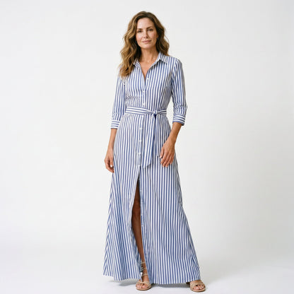 Light Blue - A woman wearing a black and white vertically striped maxi shirt dress with a collar, three-quarter sleeves, and a self-tie belt at the waist, paired with black high-heeled sandals against a plain white background.