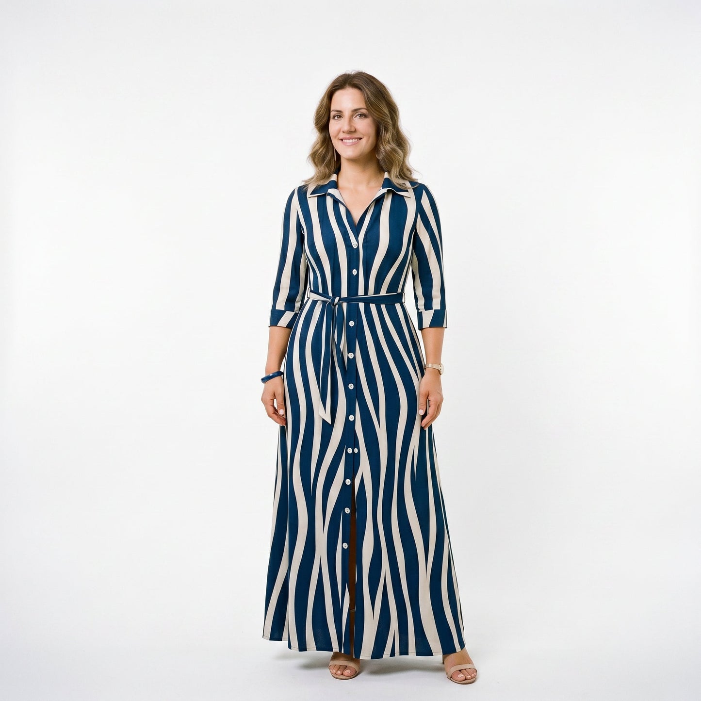 Blue - A woman wearing a black and white vertically striped maxi shirt dress with a collar, three-quarter sleeves, and a self-tie belt at the waist, paired with black high-heeled sandals against a plain white background.