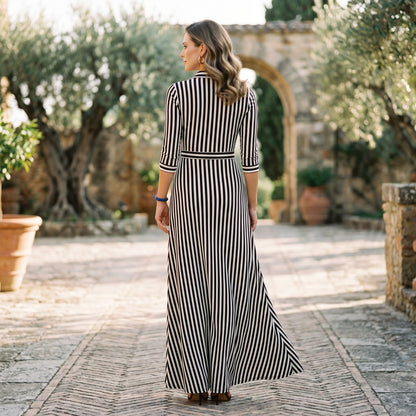 Blue - A woman wearing a black and white vertically striped maxi shirt dress with a collar, three-quarter sleeves, and a self-tie belt at the waist, paired with black high-heeled sandals against a plain white background.